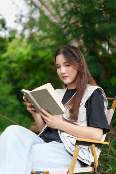 istock A hiker sitting in the forest, reading a book. She is surrounded by lush greenery, enjoying a peaceful moment in nature 2169978057