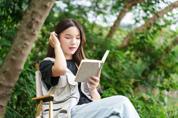 istock A hiker sitting in the forest, reading a book. She is surrounded by lush greenery, enjoying a peaceful moment in nature 2169978073