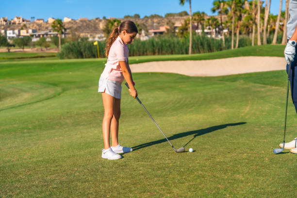 istock Girl swinging golf next to instructor 2169979134