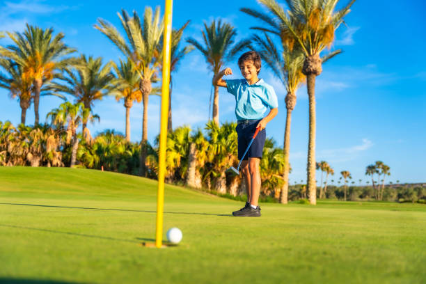 Full length photo of a caucasian boy celebrating he scores in a golf course