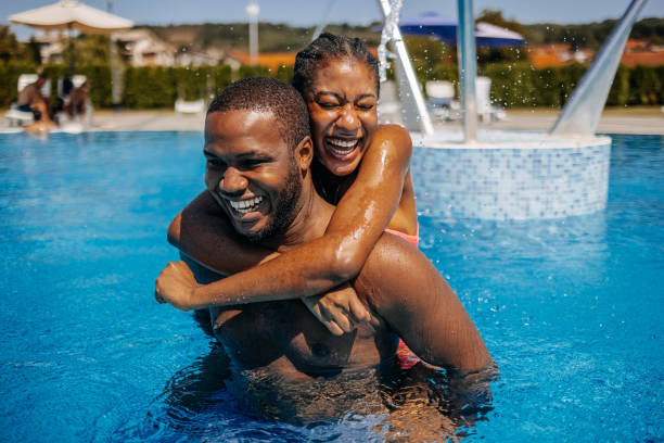 Young adults enjoying their vacation spending time in swimming pool on summer sunny day