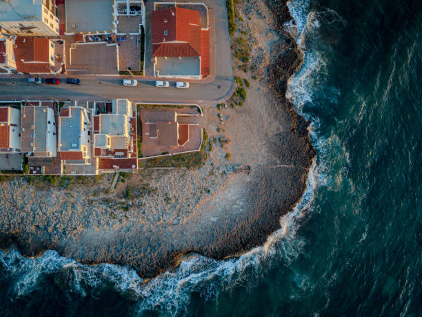 A breathtaking drone shot capturing the expansive coastline of Menorca, Spain. The image highlights the contrast between the deep blue Mediterranean Sea and the rugged cliffs, revealing the island's natural beauty.