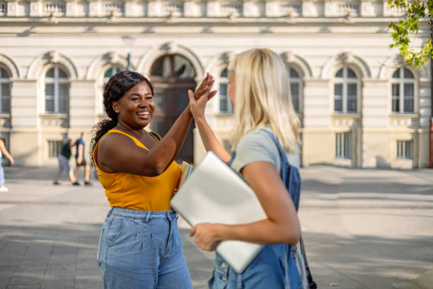 Two friends give a high-five outdoors in sunny weather