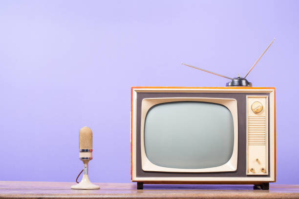 istock Microphone and retro TV with old antenna on table front purple background. Vintage style filtered photo 2169985120