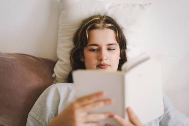 istock A woman relaxes on a couch and reads a book 2169989609