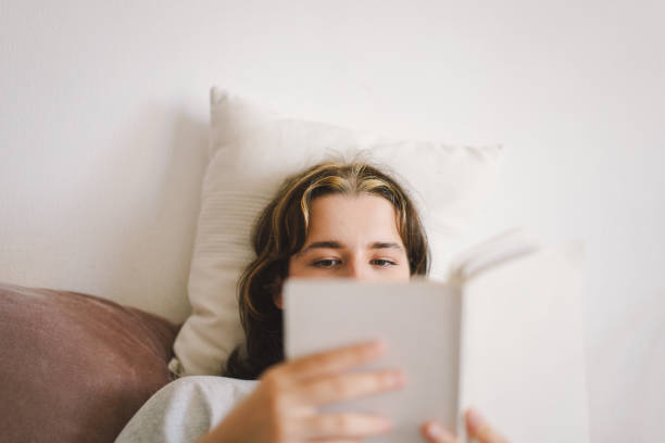 istock A woman relaxes on a couch and reads a book 2169989613