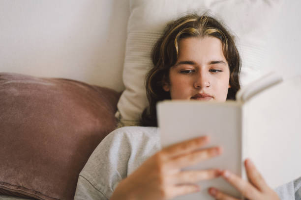 istock A woman relaxes on a couch and reads a book 2169989632