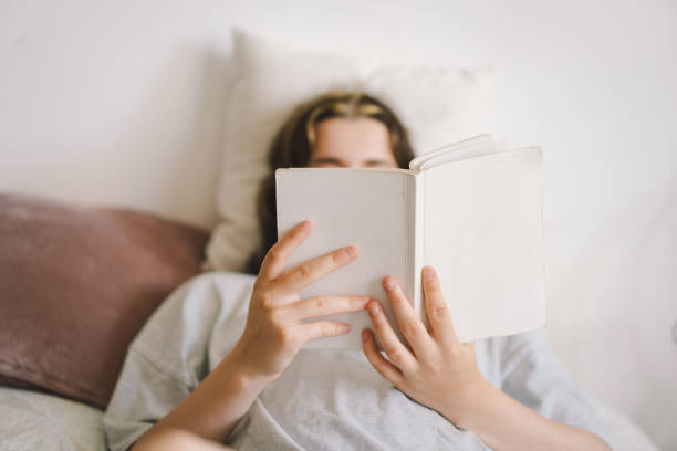 istock A woman relaxes on a couch and reads a book 2169989639