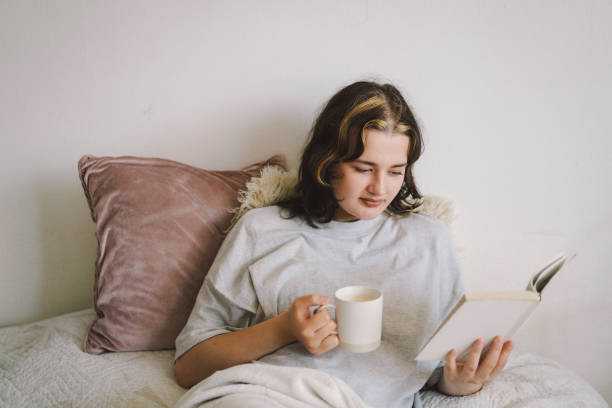 istock A woman relaxes on a couch and reads a book 2169989662