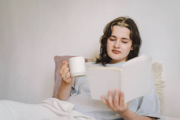 istock A woman relaxes on a couch and reads a book 2169989667