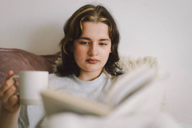 istock A woman relaxes on a couch and reads a book 2169989712