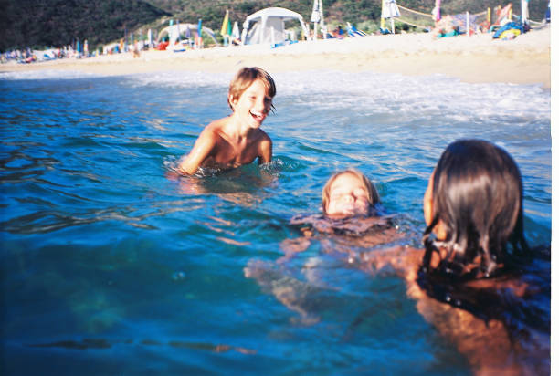 Brother and sisters enjoying sea on a beautiful sunny day. They are happy, smiling, enjoying and laughing. Shoot by film. Blurred.