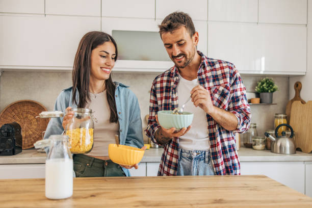 istock young cheerful couple eating cornflakes for breakfast in kitchen 2169990136
