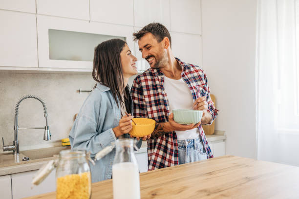 istock young cheerful couple eating cornflakes for breakfast in kitchen 2169990204