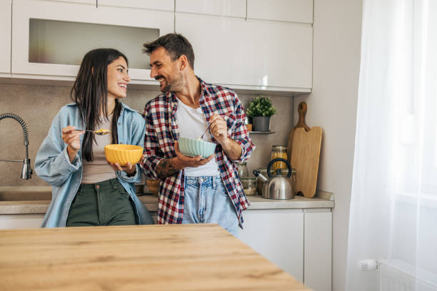 istock young cheerful couple eating cornflakes for breakfast in kitchen 2169990649