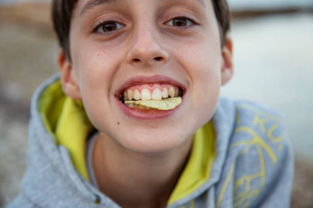 A boy is eating chips on the seashore close up