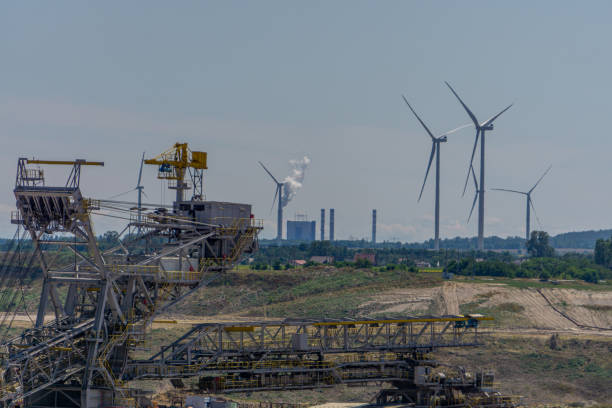 istock open-pit lignite mine. machines for digging hard coal. industrial atmosphere in the countryside on a beautiful sunny summer day. windmills, wind farms in the background. ecological and non-ecological energy sources 2169993702