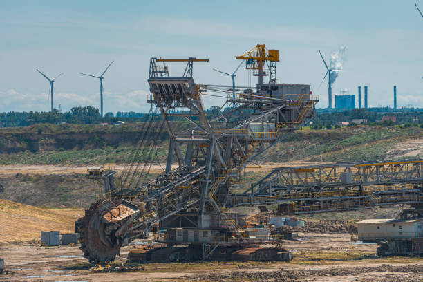 istock open-pit lignite mine. machines for digging hard coal. industrial atmosphere in the countryside on a beautiful sunny summer day. windmills, wind farms in the background. ecological and non-ecological energy sources 2169993704