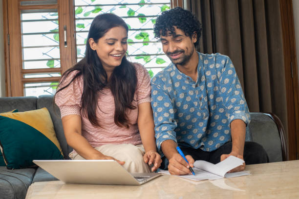istock Couple examining bills and using laptop on table at home 2169994105