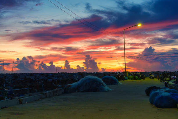 Colorful sunrise sky over stone jetty in fishing village
