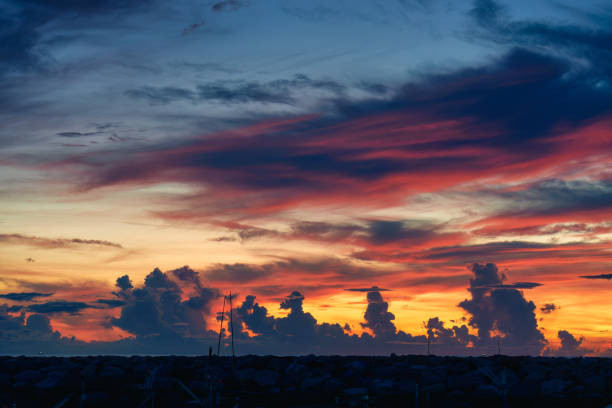 Colorful sunrise sky over stone jetty in fishing village