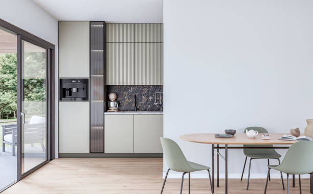 istock Modern khaki green kitchen with large windows (garden view) in the background and a dining table with chairs in front of a white blank wall in the foreground 2170001269