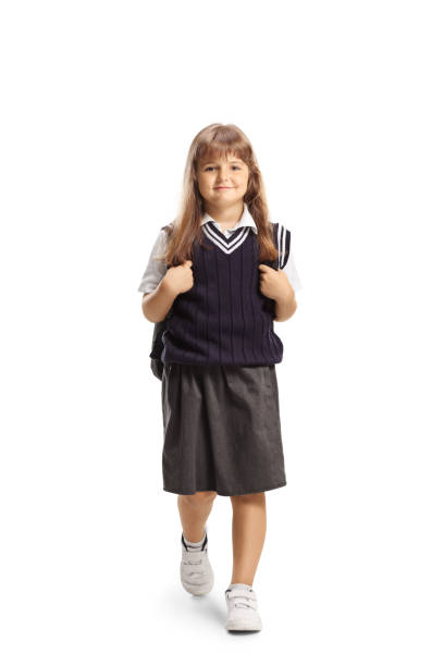 Kid in a school uniform walking towards camera isolated on white background