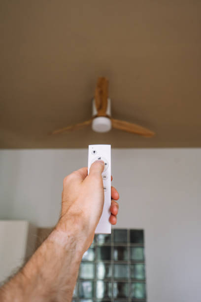 istock A person operating a ceiling fan with a remote control 2170007801