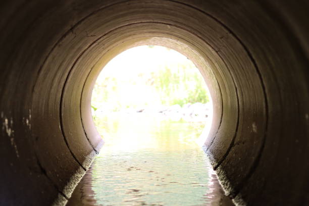 istock View through a round concrete tunnel carrying a stream beneath a road 2170007978