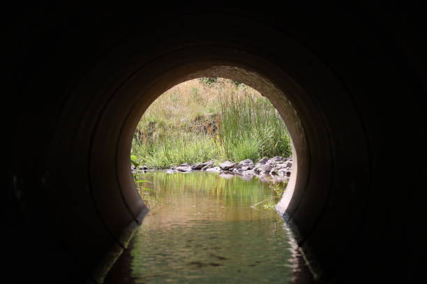 istock View through a round concrete tunnel carrying a stream beneath a road 2170008095
