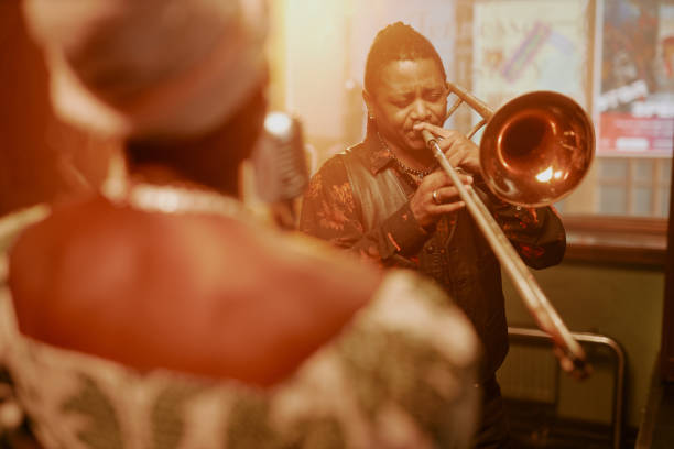 Over shoulder shot of young African American man playing trombone on stage with his jazz music band