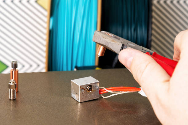 istock Hand uses pliers to replace a worn-out nozzle on a 3D printer with a new one 2170010925