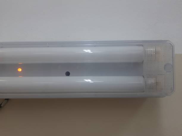istock An electric emergency lighting lamp with two bulbs that is charged and has a wall behind it. The upper part is white and the lower part is beige 2170012103