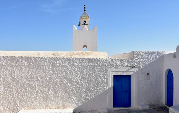 istock White Wall and Blue Doors with Modest Mosque Minaret in Takrouna, Tunisia 2170012172