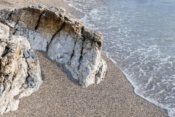 White coastal rocks lay in wet sand on the beach, natural photo