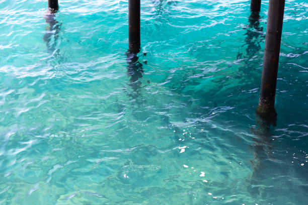 Blue sea water surface with ripple and old pier supports. Abstract background photo