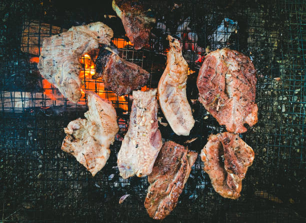 Grilled Meat on Barbecue, Closeup of Juicy Steaks and Pork Cooking Over Open Fire, High-Quality BBQ Stock Image for Food Photography and Culinary Concepts.