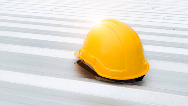 istock Features a bright yellow safety helmet resting on a clean metal roof. 2170024287