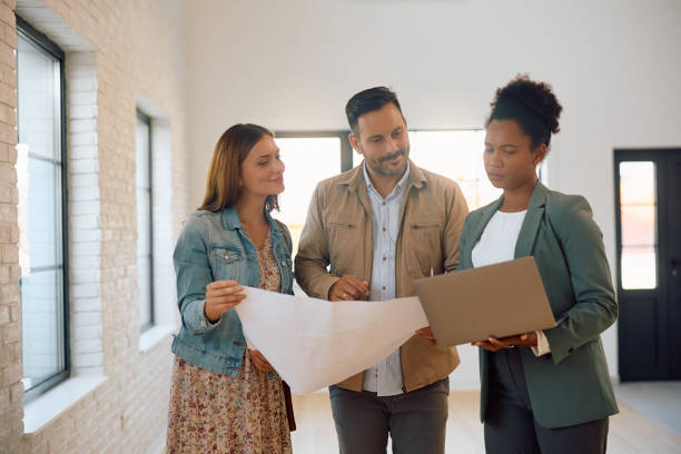 istock Smiling couple and their real estate agent using laptop while analyzing housing plans. 2170030512