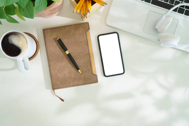 istock Top view smart phone with empty screen, notebook and coffee cup on wooden office desk. Copy space for your text. 2170033095