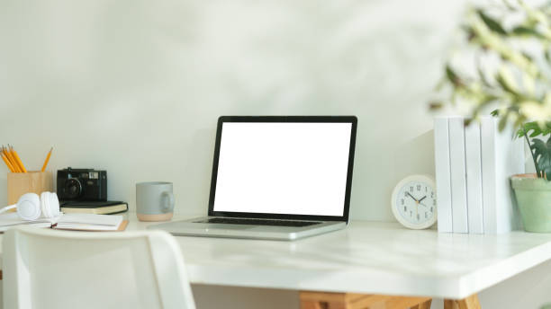 istock Minimalist workspace setup Laptop computer with blank screen, coffee cup and potted plant on white table. 2170033248