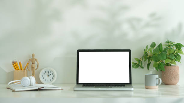 istock Front view laptop computer with blank screen, coffee cup and potted plant on white table. Home office. 2170033250