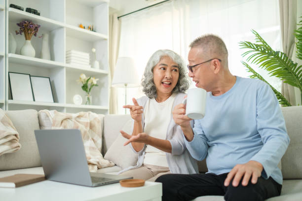 istock Elderly couple is seated comfortably on a couch, engaged in a lively conversation while enjoying a cup of coffee. 2170033425