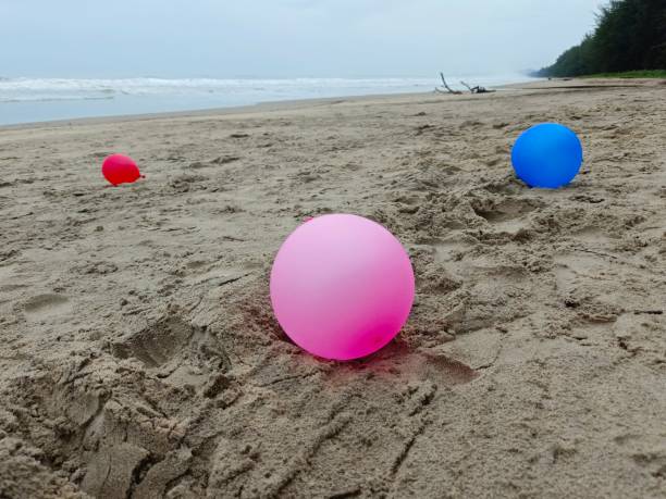istock Colourful balloons on the sand at the beach 2170034425