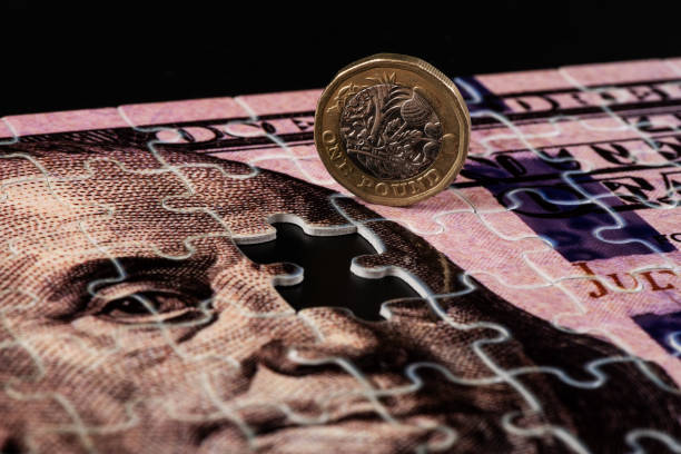 istock US $100 bill assembled from puzzles and 1 British pound coin 2170037152