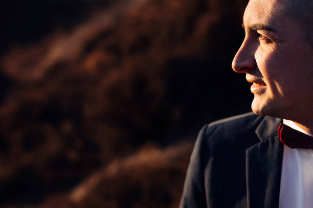 Profile groom in a black jacket and marsala bow tie. close up. wedding.