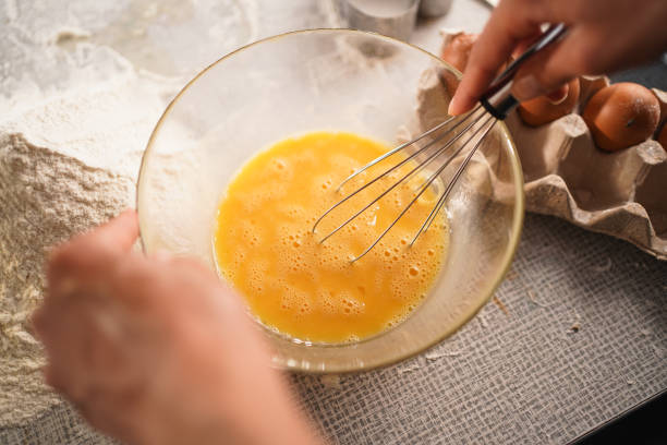 istock Hands whisking eggs in a bowl with flour on the table, preparing ingredients for baking. 2170041372