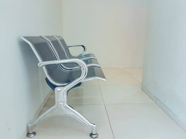 A quiet waiting area inside a railway station, featuring rows of sleek, metal perforated seating. The polished granite floor reflects the bright lighting, enhancing the clean and organized atmosphere.