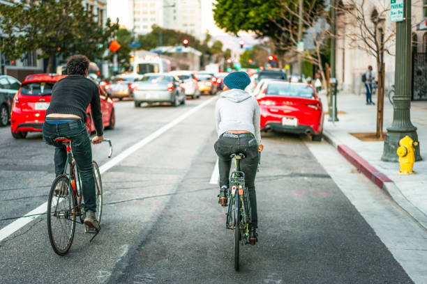 Two friends cycling side by side on the street in downtown LA.\n\nModel released image.