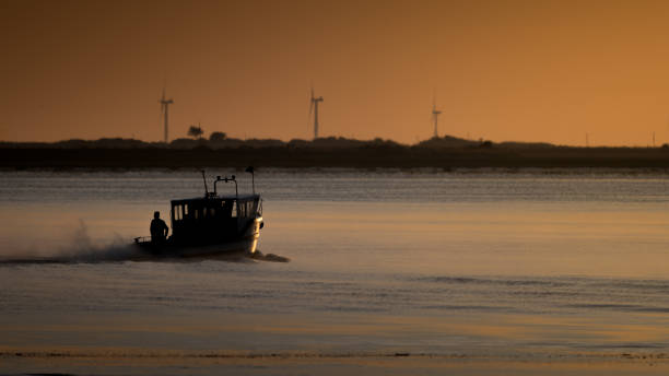 Fishing boat leaving harbour at sunrise.